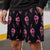 A person wearing black athletic shorts with an all-over pink skull-and-hockey stick pattern, standing in a hockey arena
