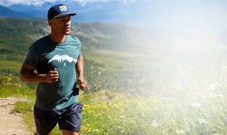 Man running on a trail with mountains in the background