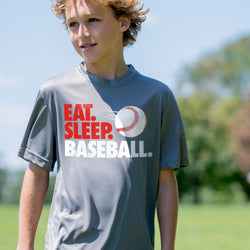 Child wearing a 'Eat. Sleep. Baseball.' t-shirt on a sports field.