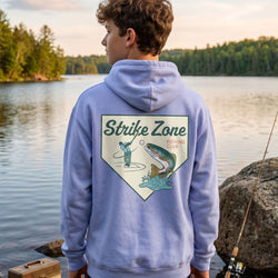 Person wearing a hoodie with 'Strike Zone Fishing Club' design by a lake.