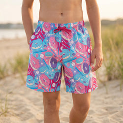 Person wearing colorful hockey donut swim shorts with a beach background