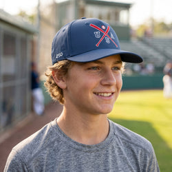 Boy wearing a usa themed baseball cap on a baseball field.