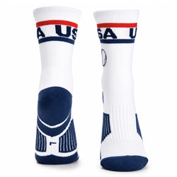 A pair of white crew socks with navy blue and red accents, featuring 'USA' printed on the cuff and a geometric pattern on the heel.