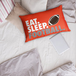 Red pillow with 'Eat. Sleep. Football.' text and football graphic on a bed.