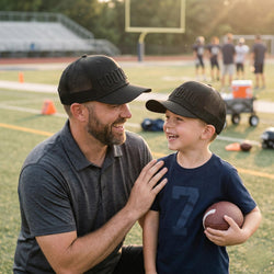Man and child on a football field with a football, wearing matching caps.