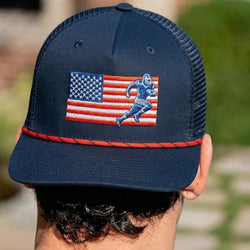 Navy blue cap with American flag and football figure design, worn by a person outdoors.