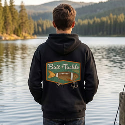 Person wearing a hoodie with 'Bait + Tackle' logo by a lake