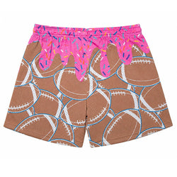 A pair of athletic shorts featuring a brown mesh fabric printed with white and blue football patterns, topped with a bright pink frosting-like graphic dripping over the waistband with colorful sprinkles.