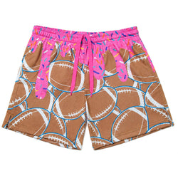 A pair of athletic shorts featuring a brown football print with pink frosting drips and colorful sprinkles, complete with a bright pink waistband and drawstring.