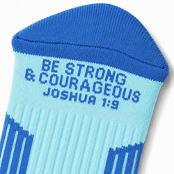 A close-up of a blue and light blue knit sock with the text 'BE STRONG & COURAGEOUS JOSHUA 1:9' printed in blue on the side.