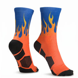 A pair of crew-length athletic socks with a flame design, featuring a blue upper leg section that fades into yellow and orange, with black reinforced zones on the heel, toe, and sole.