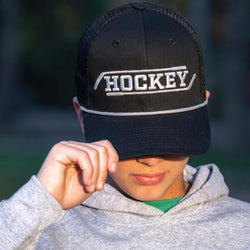 Person wearing a black cap with 'HOCKEY' on it, outdoors.