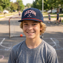 Young boy wearing a 'Hockey' cap on a playground