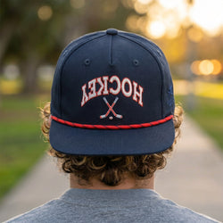 Person wearing a navy blue cap with 'HOCKEY' and crossed sticks on a blurred outdoor background