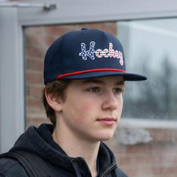 Person wearing a navy cap with 'Hockey' printed on it, standing outdoors.