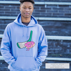 Person wearing a lightblue hoodie with a graphic design in front of a brick wall.