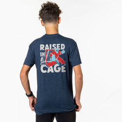Person wearing a navy t-shirt with 'Raised in a Cage' graphic on the back
