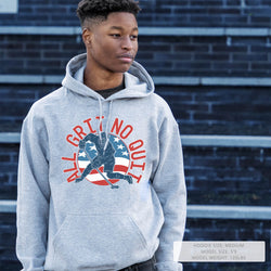 Person wearing a gray hoodie with a hockey graphic design in front of a brick wall.