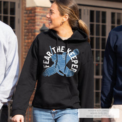 Person wearing a black hoodie with graphic design and text, standing outdoors.
