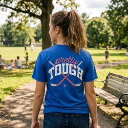 Person wearing a blue 'pretty tough' t-shirt in a park setting