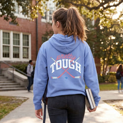 Person wearing a blue hoodie with 'Pretty Tough' text on the back, walking outdoors.