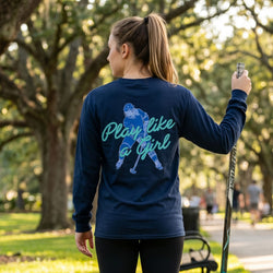 Woman wearing a navy blue long-sleeve shirt with 'Play like a girl' graphic in a park.