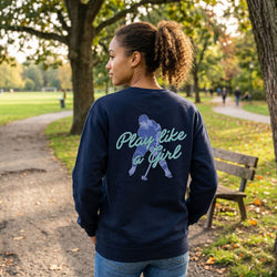 Woman wearing a navy sweatshirt with 'Play like a girl' text and graphic in a park.