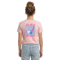 Person wearing a pink t-shirt with a hockey girl graphic design on the back, standing against a white background