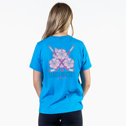 Person wearing a blue t-shirt with pink floral and hockey stick design on the back.