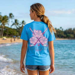 Person wearing a blue t-shirt with pink floral design on a beach