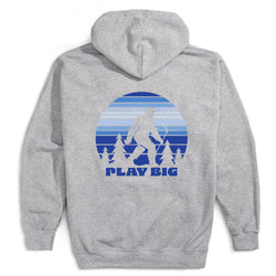 A heather gray pullover hoodie shown from the back, featuring a large blue and white graphic of a Bigfoot silhouette against a striped sunset and trees, with the text 'PLAY BIG' below.