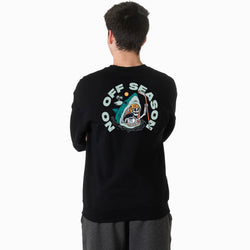 A boy wearing a black crewneck sweatshirt featuring a large graphic print on the back. The graphic shows a cartoon shark with a skeleton head holding a hockey stick, surrounded by the text 'NO OFF SEASON' in light blue, with a small beach scene in the background.