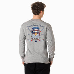 A man viewed from the back wearing a heather gray long-sleeve t-shirt with a large patriotic hockey graphic on the back, paired with black pants, against a plain white background.