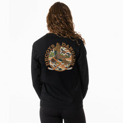 A girl viewed from behind wearing a black long sleeve t-shirt with a large graphic on the back. The graphic features the words 'DECOYS & DANGLES' in a tan font surrounding a camouflage-patterned circle with a duck and crossed hockey sticks