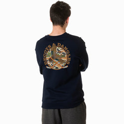 A boy viewed from behind wearing a black crewneck sweatshirt with a large graphic on the back. The graphic features the words 'DECOYS & DANGLES' in a tan font surrounding a camouflage-patterned circle with a duck and crossed hockey sticks