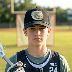 Person wearing a lacrosse fish cap and lacrosse gear on a field