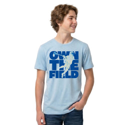 Person wearing a light blue t-shirt with 'Own the Field' graphic design on a white background