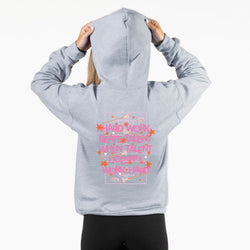 A person shown from the back wearing a light heather gray hoodie with a pink and orange graphic text print on the back, paired with black leggings, against a plain white background.