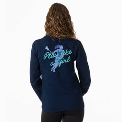 A woman viewed from the back wearing a navy long-sleeve shirt with a large graphic on the back. The graphic shows a lacrosse player in blue and teal with the text 'Play like a Girl' in teal script.
