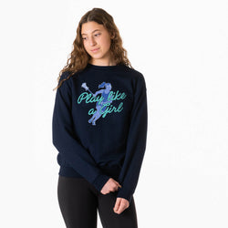 A woman modeling a navy blue crewneck sweatshirt with a graphic on the front. The graphic features a blue silhouette of a lacrosse player and the text 'Play like a Girl' in teal and light blue.