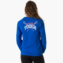 A woman viewed from the back wearing a royal blue tee with a graphic on the back that reads 'pretty TOUGH' in white and pink over crossed lacrosse sticks, against a light gray studio background.