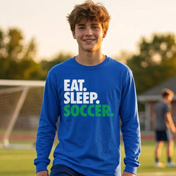 Person wearing a blue long-sleeve shirt with 'EAT. SLEEP. SOCCER.' text on a soccer field.