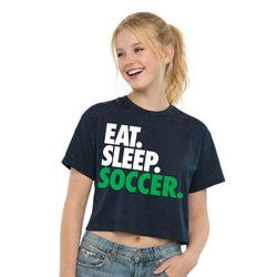 Young girl wearing a navy t-shirt with 'EAT. SLEEP. SOCCER.' text on a white background