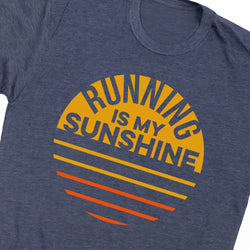 A close-up of a heather navy blue t-shirt featuring a retro-style graphic print that reads 'RUNNING IS MY SUNSHINE' in dark blue lettering, set against a yellow semi-circle with orange and yellow horizontal stripes.