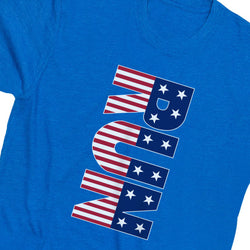 A close-up of a heather blue t-shirt featuring a large graphic print of the word 'RUN' in vertical letters, styled with an American flag pattern of red and white stripes and white stars on a navy blue background.