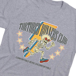 A close-up of a heather gray t-shirt featuring a retro-style graphic of a skeleton runner with the text 'TORTURED RUNNERS CLUB' and 'COMFORTABLE BEING UNCOMFORTABLE'.