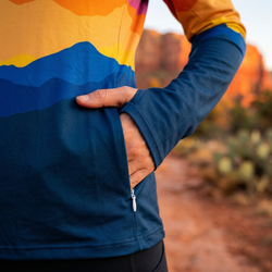 Person wearing a colorful jacket showing a side pocket with a desert landscape in the background