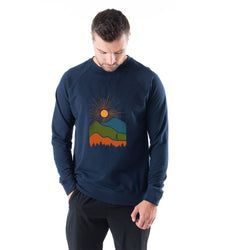 Man wearing a navy blue sweatshirt with a mountain and sun design on a white background