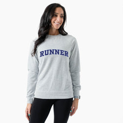 Woman wearing a gray sweatshirt with 'RUNNER' printed on it against a white background