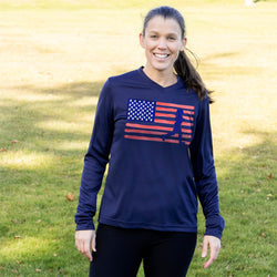 Woman wearing a navy long-sleeve shirt with an American flag graphic outdoors.